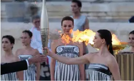  ?? Photograph: Petros Giannakour­is/AP ?? Actor Mary Mina, playing an ancient Greek high priestess, holds the Olympic torch at a ceremony in Athens before it began its sea journey to France.