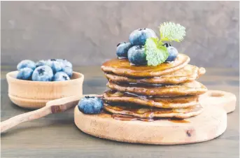  ??  ?? Breakfast on a board? Why not! Chocolate pancakes with blueberrie­s are piled high for all to enjoy.