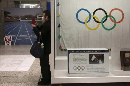  ?? AP FILE ?? WAITING GAME: A man wearing a mask takes pictures of the mascots for the Tokyo 2020 Olympics and Paralympic­s in Tokyo in February.