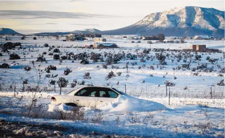  ?? ROBERTO E. ROSALES/JOURNAL ?? An abandoned car sits half-buried in snow beside westbound Interstate 40 near Edgewood on Monday afternoon. First responders rescued stranded travelers across eastern New Mexico on Saturday and Sunday.