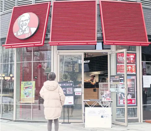  ?? CNSPHOTO VIA REUTERS ?? A customer waits to pick up her order outside a KFC restaurant where a table is set up at the entrance for contactles­s pick-up of orders placed online in Chengdu, Sichuan province.