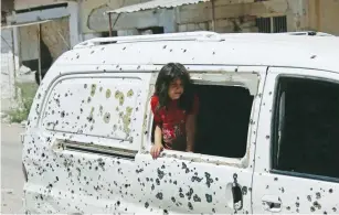  ?? (Alaa Al-Faqir/Reuters) ?? A GIRL peers from a bullet-riddled vehicle yesterday in a rebel-held part of the southern Syrian city of Deraa.