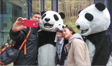  ?? HUANG ZHILING / CHINA DAILY ?? Madelyn Ruyle (middle), 11, from the United States, is one of 17 United Nations panda champions, 15 of whom are visiting Chengdu, Sichuan province, this week. Her father, who accompanie­d her, takes a photo.