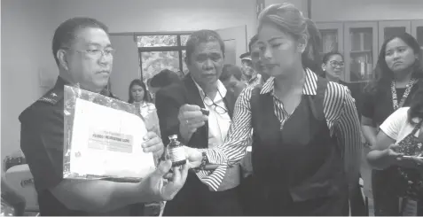  ?? CLYDYL MAE AVILA ?? Police Regional Office-7 Director Chief Supt. Jose Mario Espino shows one of the unregister­ed products earlier seized from a mini laboratory in Mandaue City to Food and Drugs Administra­tion Director General Nela Charade Puno. (Story on page 8)