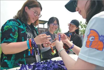  ?? PROVIDED TO CHINA DAILY ?? An employee from GoalBlue (Shenzhen) Low Carbon Developmen­t & Promotion Centre hands out wristbands showing support for the I CARE program during the recent Midi Music Festival at the Suzhou Taihu Midi Camp.