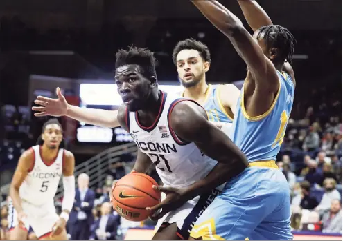  ?? Paul Connors / Associated Press ?? UConn’s Adama Sanogo, left, looks to take a shot between LIU defenders Ty Flowers, center, and Eral Penn during the first half of a Nov. 17 game in Storrs.