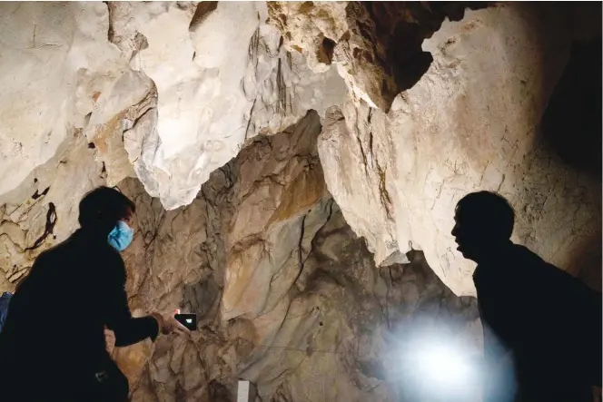  ??  ?? Visitors look inside the abandoned Wanling cave near Manhaguo village in southern China’s Yunnan province on Wednesday, Dec 2, 2020. Villagers said the cave had been used as a sacred altar presided over by a Buddhist monk — precisely the kind of contact between bats and people that alarms scientists. (AP)