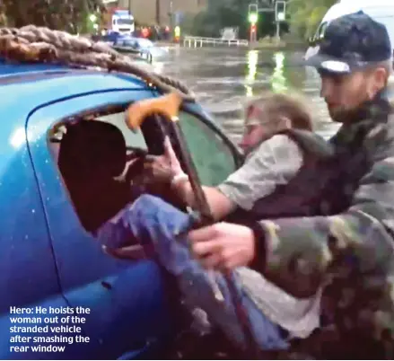  ??  ?? Hero: He hoists the woman out of the stranded vehicle after smashing the rear window