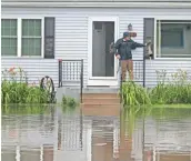  ?? MIKE DE SISTI / MILWAUKEE JOURNAL SENTINEL ?? Jason O'Donnell dumps water from his boot after water flooded up to the front of his house on Pine St. in Burlington. He said he had about 4 feet of water in his basement.