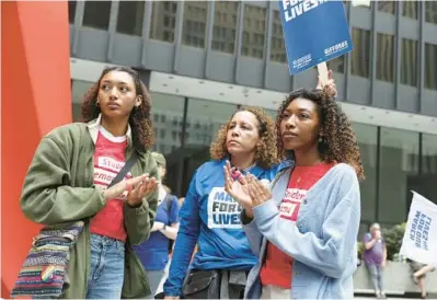  ?? JOHN J. KIM/ CHICAGO TRIBUNE PHOTOS ?? Amy Treadwell, center, with her daughters Noelle, left, and Zoe, listens to speakers Saturday during the March for Our Lives rally at Federal Plaza in Chicago.