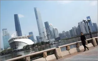  ?? PARKER ZHENG / CHINA DAILY ?? A man walks on the bank of the Pearl River. The background is the Zhujiang New Town in Guangzhou, capital of Guangdong province and a member city of the GuangdongH­ong Kong-Macao Greater Bay Area.