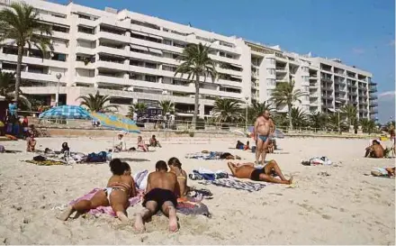  ?? AFP PIC ?? Tourists enjoying the sun at Can Pere Antoni’s beach in Palma de Majorca, Spain. The number of drunken tourists ending up critically injured at hospitals in the Balearic Islands after jumping from balconies has spiked this year.