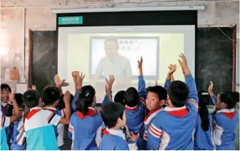  ??  ?? Students from Xiangjinzh­ang Primary School in Gaozhuang Village of Huixian County, Xinxiang City, Henan Province interact with one of Beijing's best teachers conducting a class online. Through online education, quality teaching resources can benefit less- developed areas. VCG