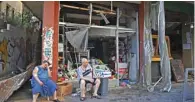  ??  ?? An injured Lebanese woman sits in front of her damaged shop in the trendy Beirut neighborho­od of Mar Mikhael.