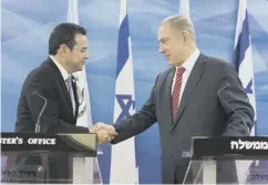  ??  ?? 0 Jimmy Morales, left, and Benjamin Netanyahu shake hands