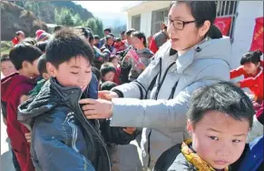  ?? LI JIANQIANG / FOR CHINA DAILY ?? Volunteers give away clothes, books and toys to more than 100 left-behind children in Bijie, Guizhou province, in February last year.