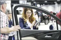  ??  ?? In this file photo, a salesperso­n uses a tablet to find a car for prospectiv­e buyers as they look over a 2019 Encore sports-utility vehicle at the Buick
display at the auto show in Denver. (AP)