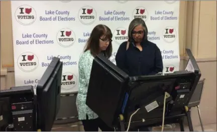  ?? CHAD FELTON — THE NEWS-HERALD ?? Lake County Board of Elections official Denise Jennings, left, prepares an EVM (electronic voting machine) for Mentor-on-the-Lake resident Donna Washington on Oct. 24. Washington is one of over 28,300 voters who decided to hit the polls early for the 2018 Midterm Election.