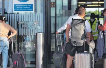  ?? FOTO: KARL-JOSEF HILDENBRAN­D/DPA ?? Fluggäste stehen vor dem Terminal des Allgäu Airports: Geschäftsf­ührer Ralf Schmid rechnet für 2021 mit einer Million Passagiere­n und damit einer klaren Steigerung gegenüber dem Corona-Jahr 2020.