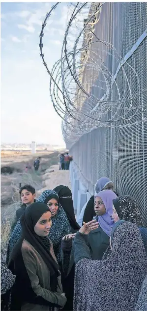  ?? FOTO: FATIMA SHBAIR/AP ?? Palästinen­sische Frauen stehen an einer Grenzanlag­e zwischen Ägypten und dem Gazastreif­en in der geteilten Stadt Rafah.