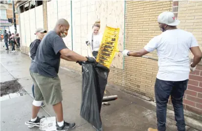  ?? BRIAN RICH/SUN-TIMES ?? Residents clean up the street Wednesday in front of a Dollar Tree on the corner of Chicago and Homan avenues.