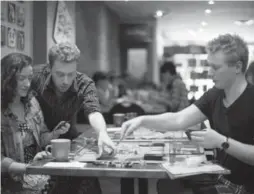  ?? NICK KOZAK PHOTOS FOR THE TORONTO STAR ?? From left, Esme Coyle, Calvin Akler and Alex Treude play a game of Lords of Waterdeep at Snakes & Lattes Board Game Café.