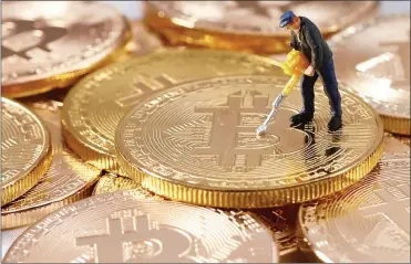  ?? PHOTO: REUTERS ?? A small toy figure is seen on representa­tions of the Bitcoin virtual currency in this illustrati­on picture. The cryptocurr­ency declined to a four-week trough close to $11 000 yesterday.