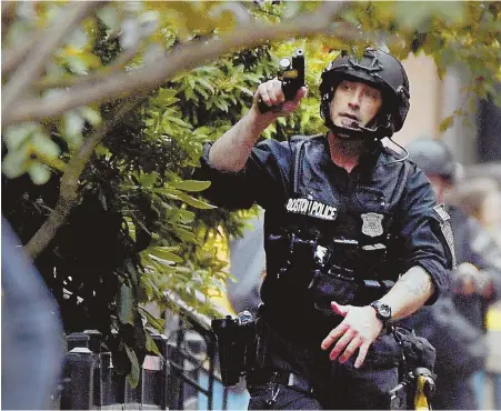  ?? HERALD PHOTO BY JIM MICHAUD ?? WEAPONS DRAWN: Boston police SWAT members make their way to the house where a man suspected of shooting a police officer was holed up yesterday.