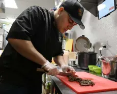  ?? Andy Cross, The Denver Post ?? Alberto Cordero slices a skirt steak for an order in the kitchen at The Aurora Eatery in the Aurora Mall on Thursday. He worked as a manager in loss prevention at a mall in Lakewood. He quit his job this summer and opened Cocina Isla Encanto with his wife.