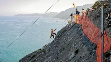  ?? PHOTO: DAVID WALKER/STUFF ?? Abseilers perched high above State Highway 1, south of Kaiko¯ura, work at stabilisin­g slip sites with wire mesh.