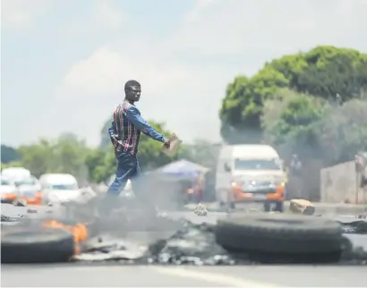  ?? Picture: Alaister Russell ?? FIRED UP. Residents pass road blockades outside the Central Johannesbu­rg College in Alexandra, Johannesbu­rg, yesterday.