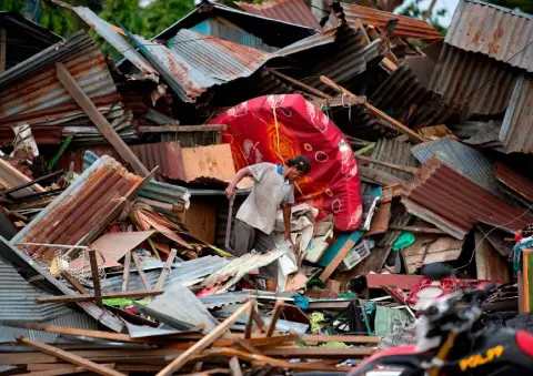  ??  ?? HEARTBREAK: A man searches for his belongings among the debris of his wrecked house in Palu on Sulawesi yesterday after a wave at least 10ft high barrelled inland, killing 384 people and submerging single-storey buildings. Photo: Bay Ismoyo