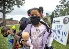  ?? STAFF PHOTO BY TROY STOLT ?? Faith Pruitt, 5, stands outside the East Lake Courts Community Center on Thursday as her mother, Dominique, tries to put a mask on her 2-year-old brother Nehemiah.