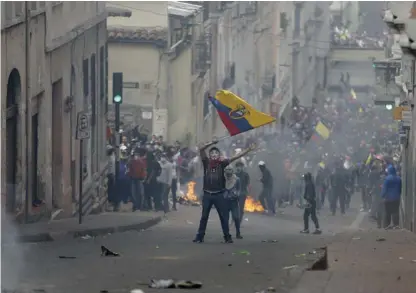  ?? AP ?? Un manifestan­te ondea una bandera de Ecuador durante los enfrentami­entos en el centro de Quito, Ecuador. La crisis en esa nación no parece aplacarse.