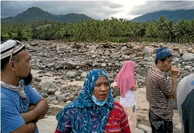  ?? PHOTO: GETTY IMAGES ?? Residents look at what is left of their village in Salvador, Lanao del Norte province after Typhoon Tembin swept across the southern Philippine­s.