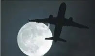  ?? JUSTIN TALLIS / AGENCE FRANCE-PRESSE ?? A plane flies in front of a “supermoon” on its approach to London Heathrow Airport on London on Monday.