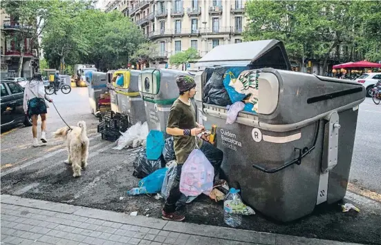  ?? ANA JIMÉNEZ ?? Un vecino de la calle Enric Granados comprueba que sus bolsas no caben en un contenedor de resto, desbordado ya durante la tarde