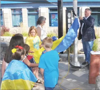  ?? ?? Mayor Al Bridal raises the Ukrainian flag with assistance from children present at the event, Aug. 24.