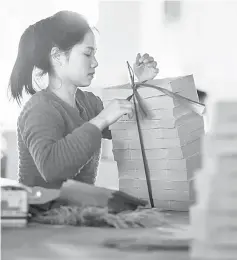  ??  ?? A worker in Shantou sorting ‘spirit money’.