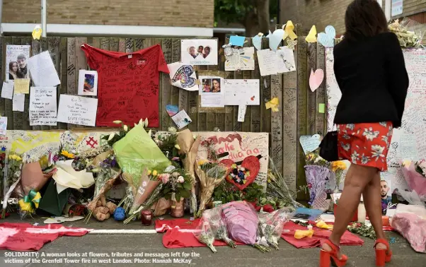  ??  ?? SOLIDARITY: A woman looks at flowers, tributes and messages left for the victims of the Grenfell Tower fire in west London. Photo: Hannah McKay