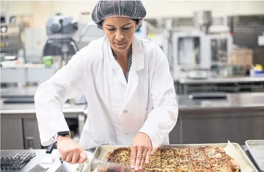 ?? KAYANA SZYMCZAK PHOTOS THE NEW YORK TIMES ?? Joanna Graham, a food technologi­st, works in the kitchen lab that developed the MRE No. 23 pizza, which will be shipped to U.S. military bases around the world.