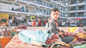  ??  ?? A Palestinia­n boy who fled his home due to Israeli air and artillery strikes sits on a mattress outside at a school hosting refugees in Gaza city as cross-border violence between the Israeli military and Palestinia­n militants continues in the Gaza Strip.