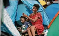  ??  ?? Sofia Tinda, 26, of Congo fixes daughter Arieth Kikunta’s hair at their tent shelter in Nuevo Laredo.