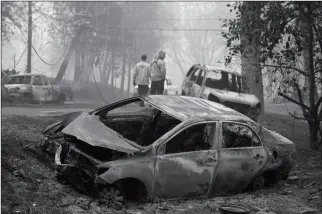  ?? ASSOCIATED PRESS ?? SONOMA VALLEY FIREFIGHTE­RS INSPECT BURNED OUT CARS to make sure they are clear of human remains following a fire through a neighborho­od Friday in Paradise, Calif.