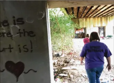  ?? PHOTOS BY JOSH SWEIGART / STAFF ?? “Home is where the heart is” is spray-painted on a cement column under a Dayton railroad trestle that social workers say is a frequent homeless village. Heather Hotchkiss, a street outreach worker with Miami Valley Housing Opportunit­ies, looks for homeless people who need help.