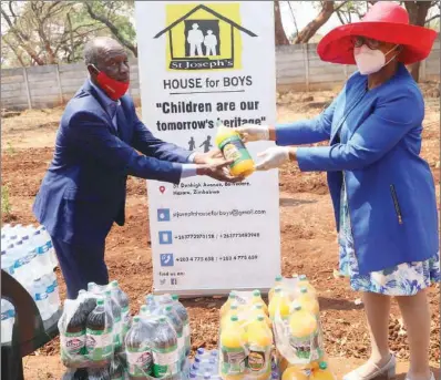  ??  ?? St Joseph’s House for Boys board member Philip Katsande receives a donation of flavoured drink and bottled water from Seed Co spokespers­on Marjorie Mutemererw­a during the planting of trees in memory of her late son, Richard Kelvin Rugube