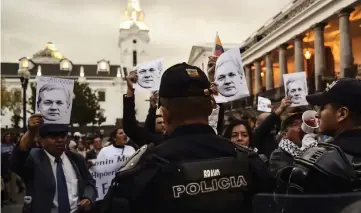  ??  ?? Police officers stand guard as supporters of former Ecuadoran president Rafael Correa, take part in a demonstrat­ion outside Carondelet presidenti­al palace in Quito, to show their support to Assange. — AFP photo