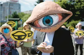  ?? VADIM GHIRDA/AP ?? An activist wears a mask of an eyeball during a protest of proposed updates to national security laws Wednesday in Bucharest, Romania. Proposed changes to the laws would give added power to Romania’s intelligen­ce service and calls for citizens and companies to cooperate with the service if requested to do so.