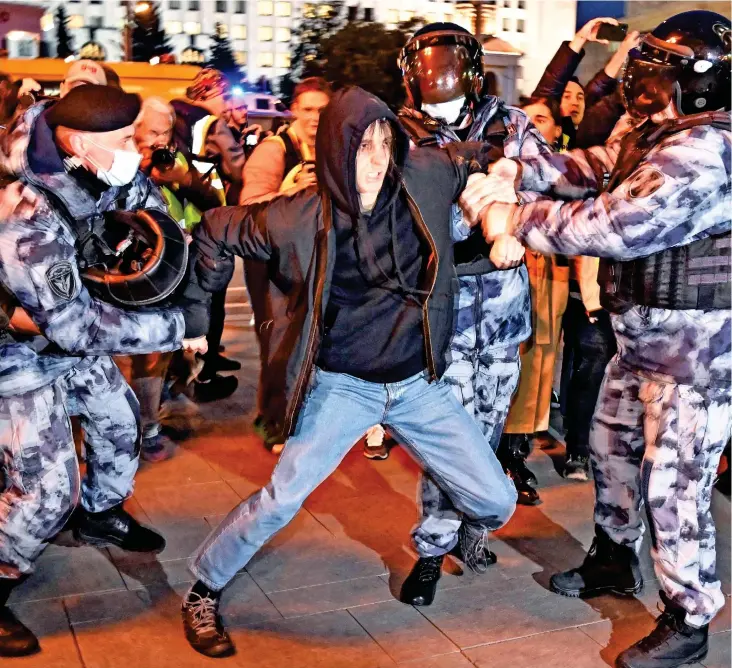  ?? ?? No escape: A demonstrat­or’s face is frozen in fear as he tries to shake himself free from the grasp of Putin’s heavily-armoured police in Moscow last night