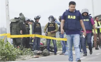  ??  ?? DHAKA: Bangladesh Rapid Action Battalion (RAB) personnel and bomb experts stand near the body of a man beside a RAB checkpoint in Khilgaon.